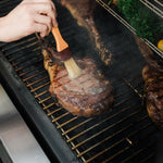 Côte de bœuf arrosée pendant la cuisson sur le Masterbuilt Gravity Series XT